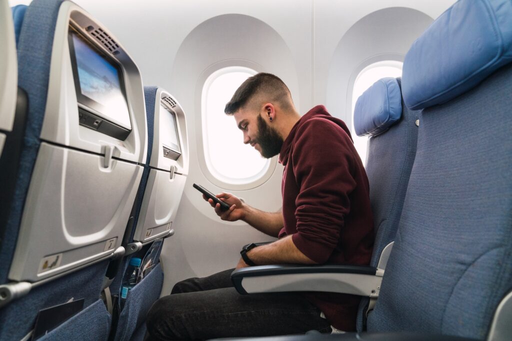 Bearded guy using smartphone in plane
